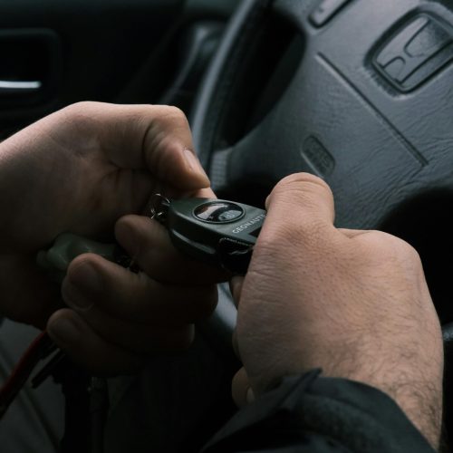 Close-up of hands holding a compass in a car interior setting, hinting navigation.